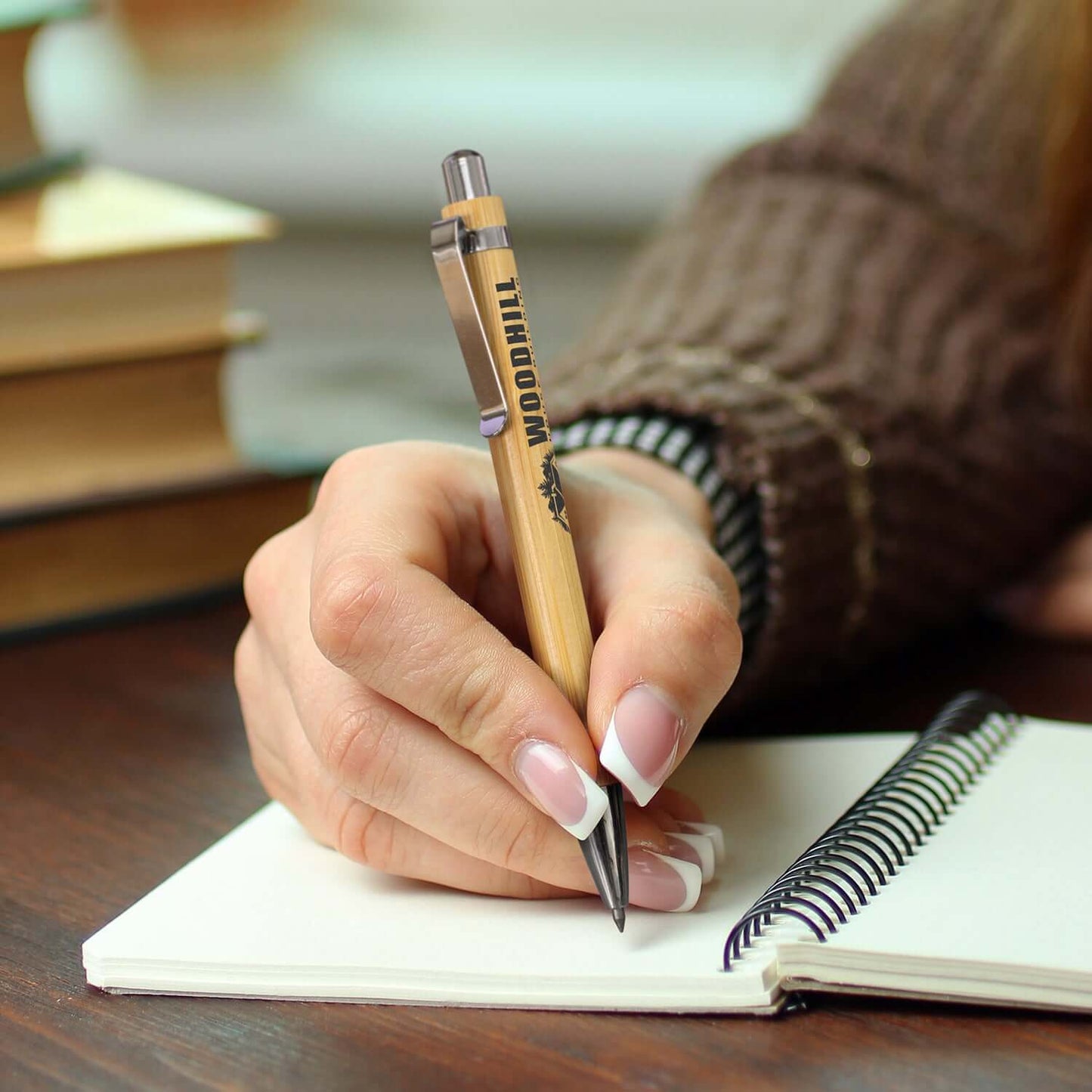 Ancona Bamboo Inkless Pen being used to write in a notebook, perfect for corporate gift ideas.