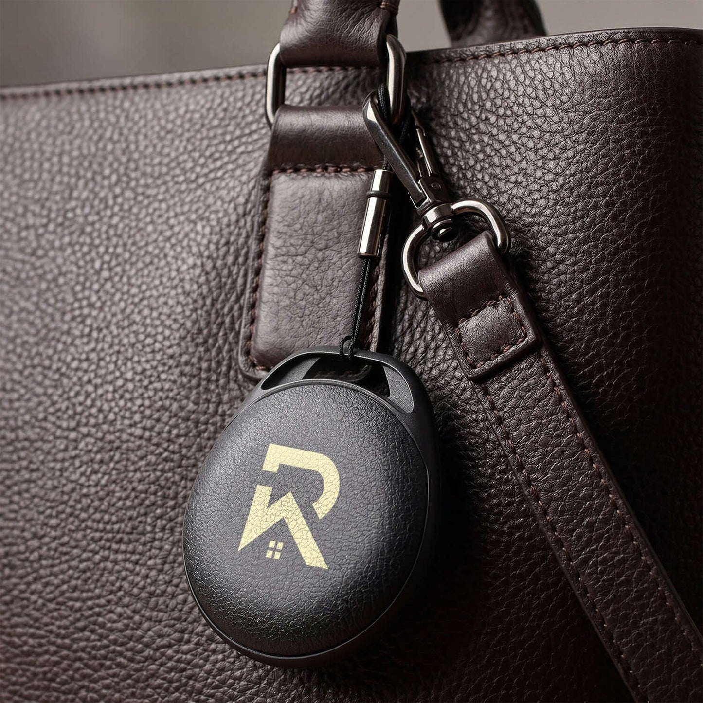 HangFindy Bluetooth Tracker attached to a stylish brown bag, serving as a practical corporate gift.
