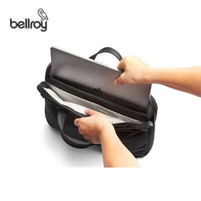 Person placing a laptop into the Bellroy Tokyo Laptop Bag 14" for organized protection and easy access.