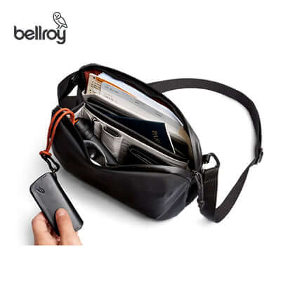 Bellroy Venture Travel Crossbody opened with organized items for travel, including passport and wallet, ideal corporate gift.