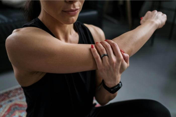 Woman stretching her arm while wearing the Prixton Orbyt Smart Ring for health tracking.