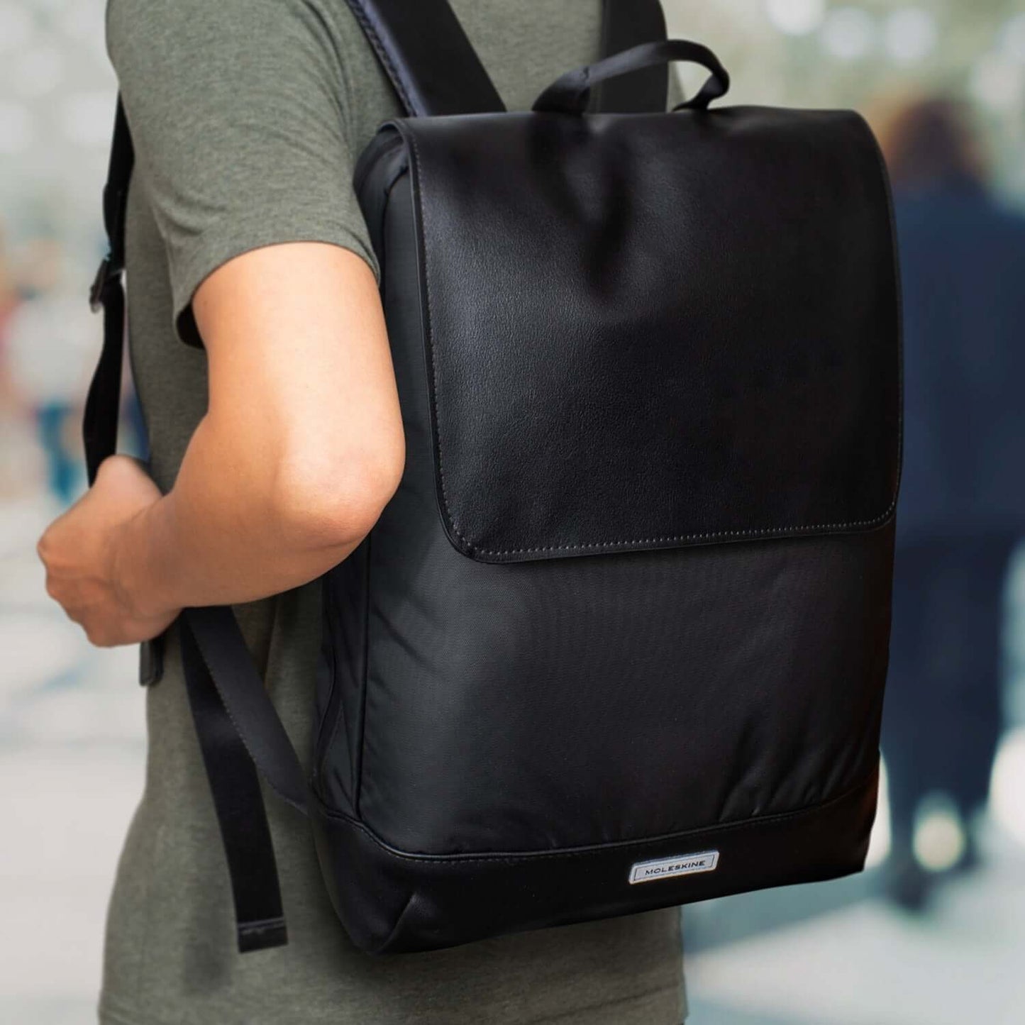 Moleskine Metro Slim Backpack worn by a person, showcasing its sleek black design and urban style.