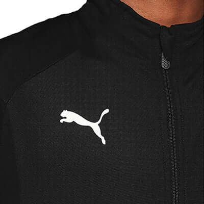 Close-up of the Puma Liga Training Jacket featuring the iconic Puma logo in white on a black fabric background.