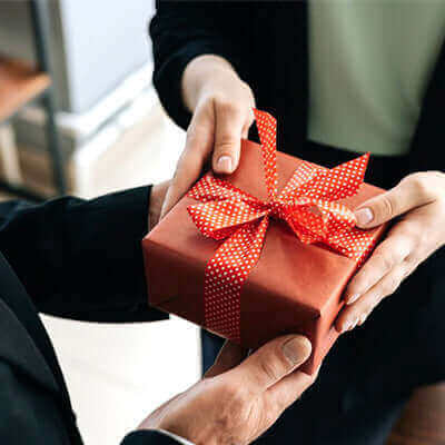 Hands exchanging a beautifully wrapped corporate gift, showcasing the essence of Impress and Inspire: The Power of Premium Corporate Gifts.