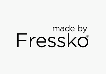 Made By Fressko pink reusable cup on a stylish leather bag with magazines, perfect for corporate gift ideas.