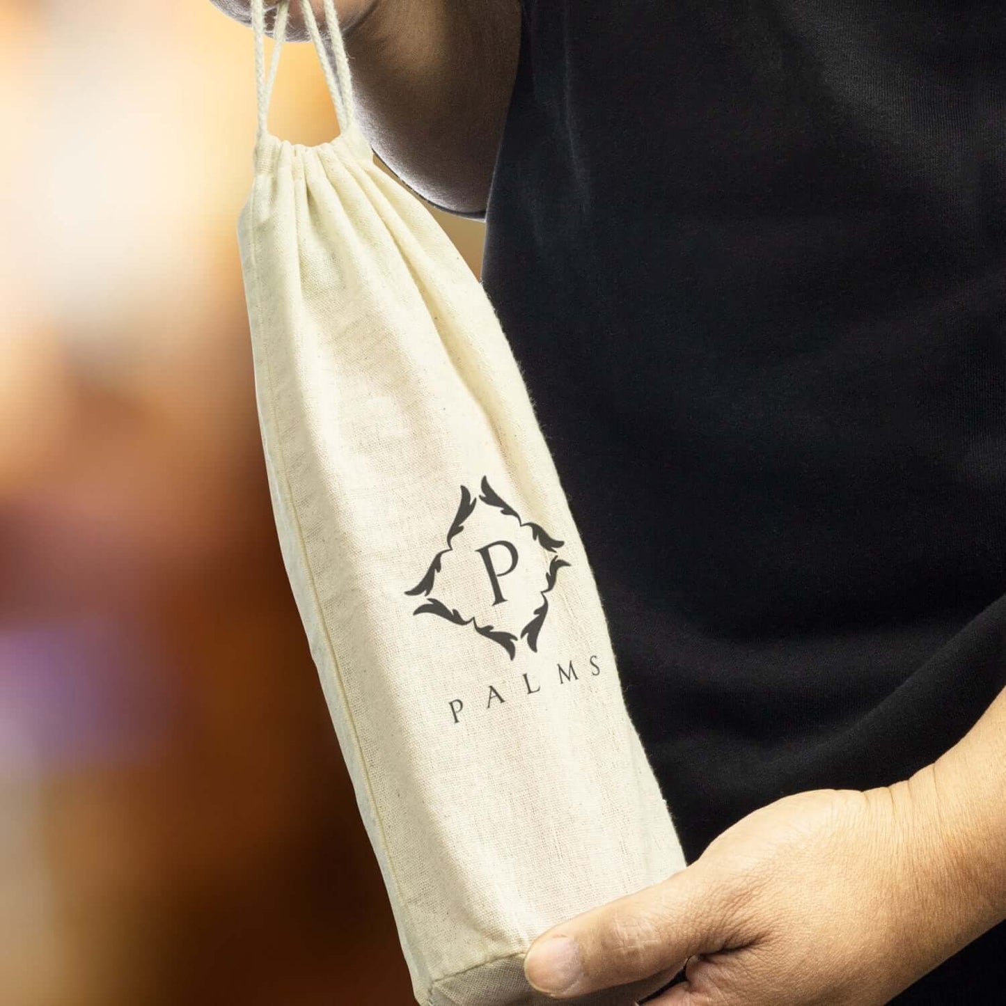 Cotton Bottle Gift Bag held by a person, featuring a drawstring closure and stylish logo for corporate gifting.