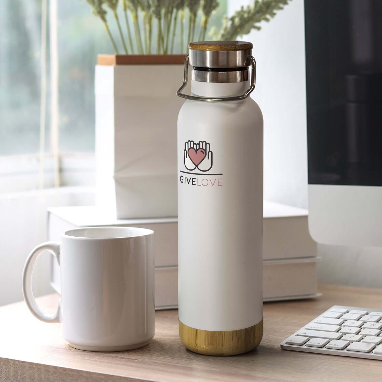 Nomad Vacuum Bottle - Bambino on a desk next to a white mug, showcasing its stylish design for everyday use.