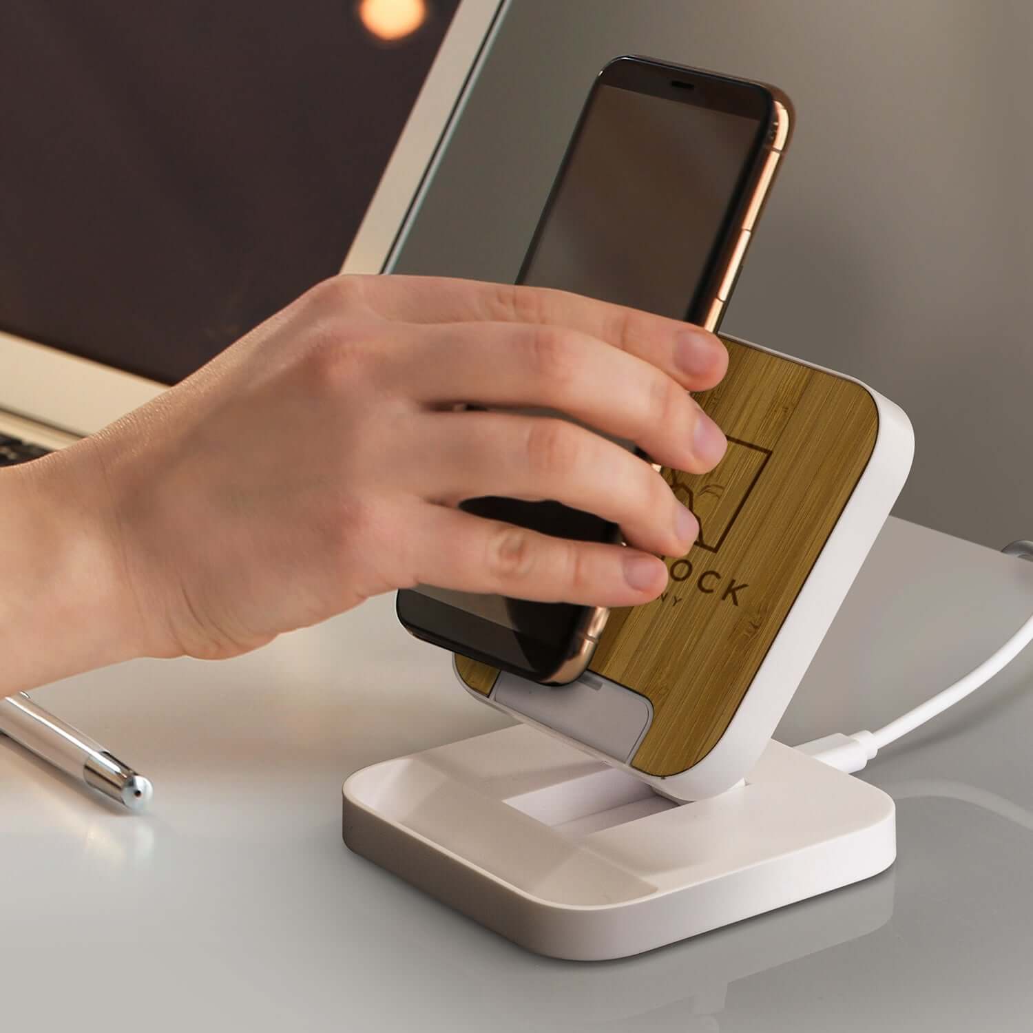 Person placing a smartphone on the Flex Wireless Fast Charging Stand with a natural bamboo panel.