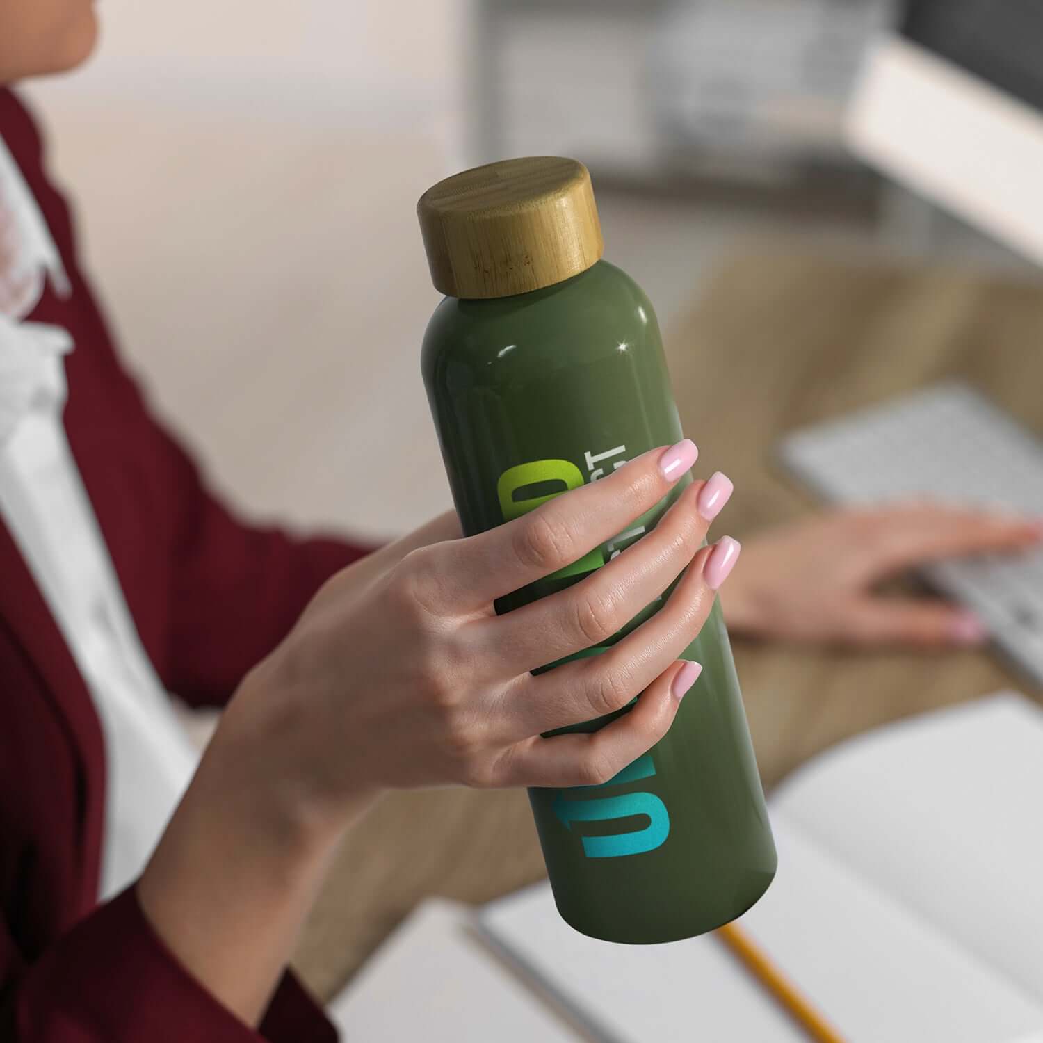 Woman holding Eden Aluminium Bottle Bamboo Lid with bamboo screw-on lid on a desk.