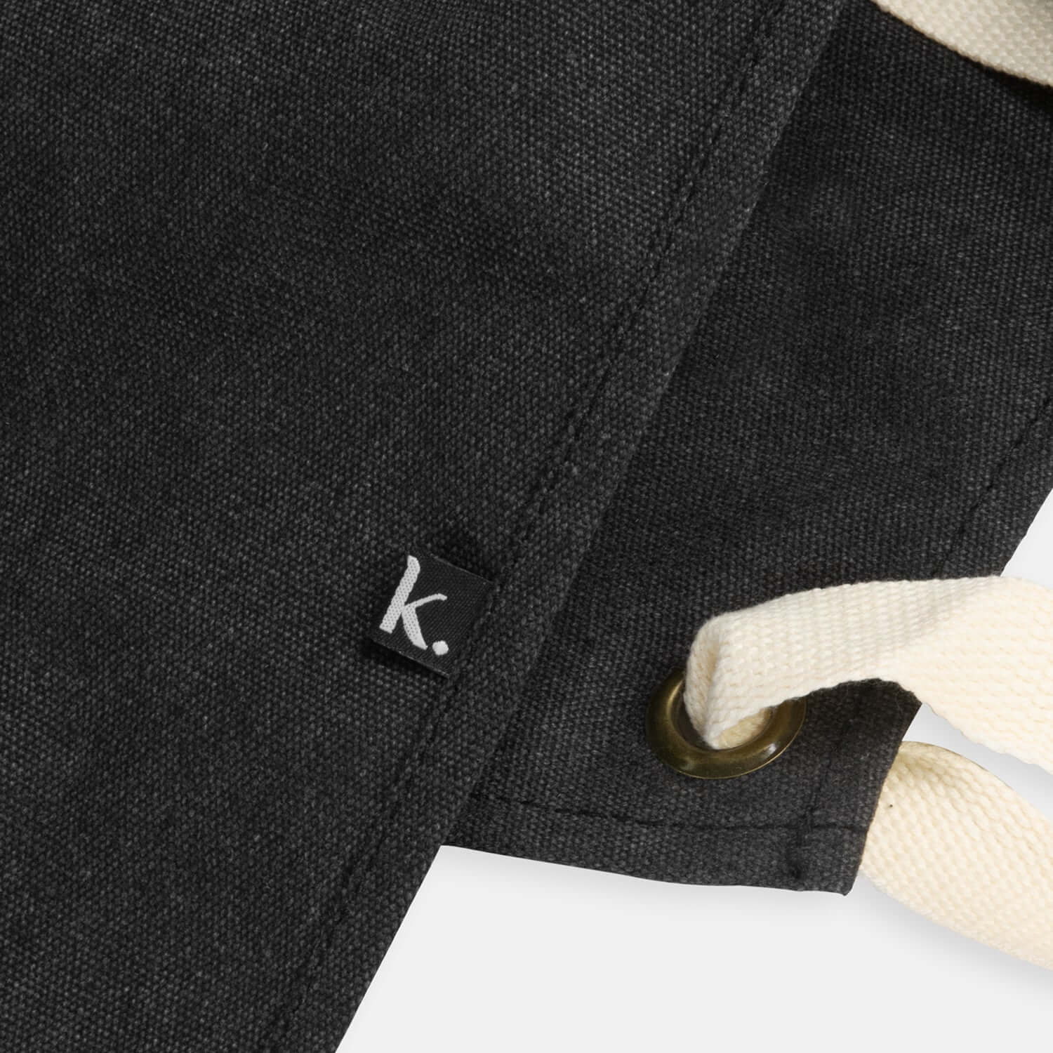 Detailed view of the Keepsake Canvas Apron showing the chic washed black fabric and woven Keepsake label.