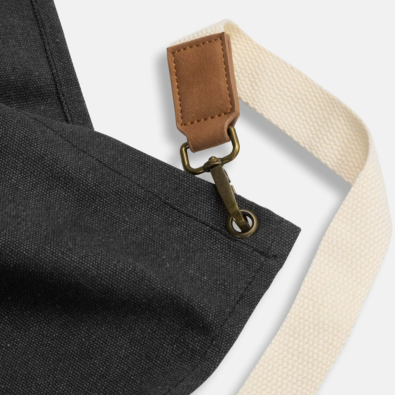 Detail of the Keepsake Canvas Apron showing leather-look pocket and adjustable cotton strap.