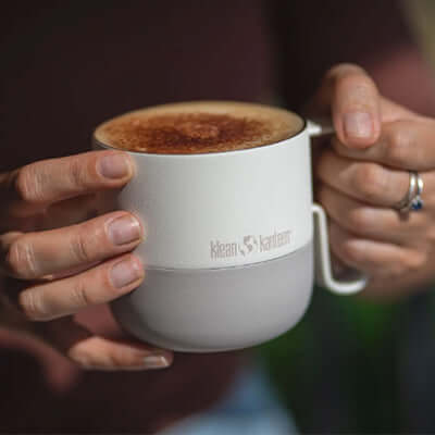 Person holding Klean Kanteen Rise 14oz Mug (with Flip Lid) filled with coffee, showcasing its sleek design.