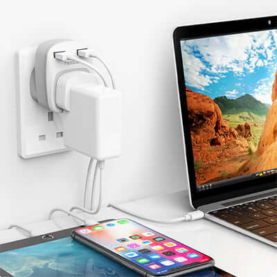 TESSAN USB Plug Adaptor with 2 USB Ports charging devices on a desk next to a laptop.