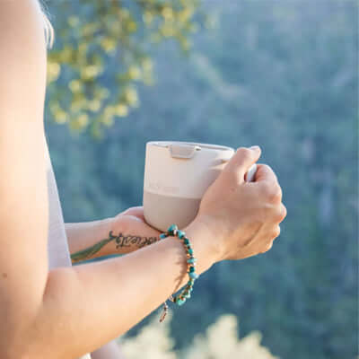 Person holding the Klean Kanteen Rise 14oz Mug (with Flip Lid) outdoors, showcasing its design and comfort.