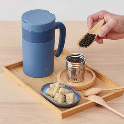 ZOJIRUSHI SE-KAE48 0.48L Vacuum Tumbler with infuser and tea on wooden tray.