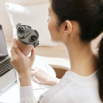 Person holding ZOJIRUSHI SX-KA30 0.3L Vacuum Tumbler while working on a laptop.