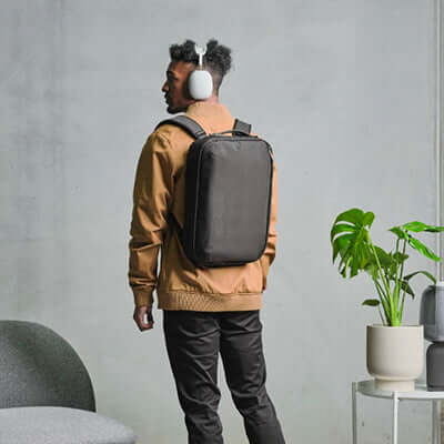 Person wearing Alpaka Tech Brief Pro 600D Backpack while listening to music with headphones.
