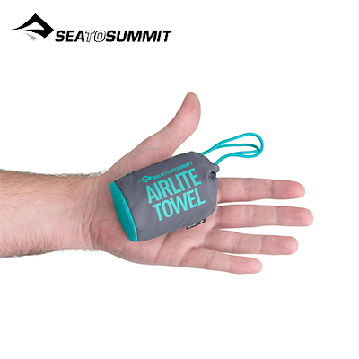 Sea To Summit Airlite Towel Large packed in hand, showcasing its compact size, ideal for outdoor adventures.