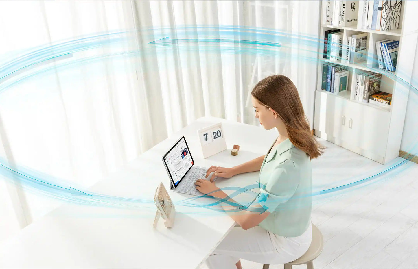 Woman enjoying the cooling airflow from the JisuLife Table Fan Life1 while working on her laptop.