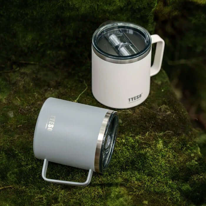 TYESO Coffee Mug 14oz in grey and white on a mossy surface, ideal corporate gift for hot and cold beverages.