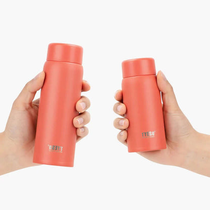 Two hands holding TYESO Mini Pocket Bottle 7oz in coral color, perfect for hydration on the go and corporate gifts.