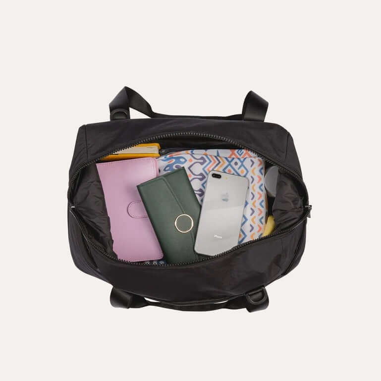 Bagsmart Zoraesque Duffel Bag interior packed with essentials including wallet, phone, and colorful items.