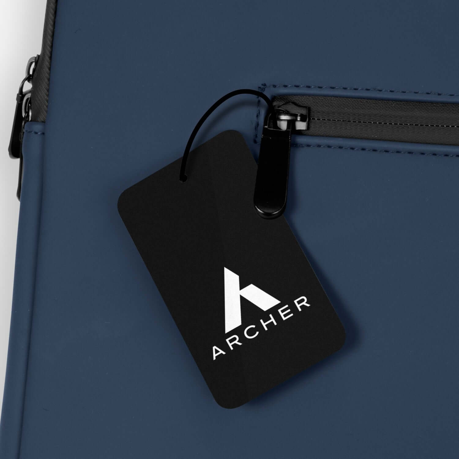 Close-up of ARCHER brand tag on Soft-Touch Laptop Sleeve in navy blue, showcasing its sleek design.
