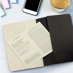 Moleskine Cahier Journal opened on a desk with a smartphone and coffee, ideal for Corporate Gift Singapore.