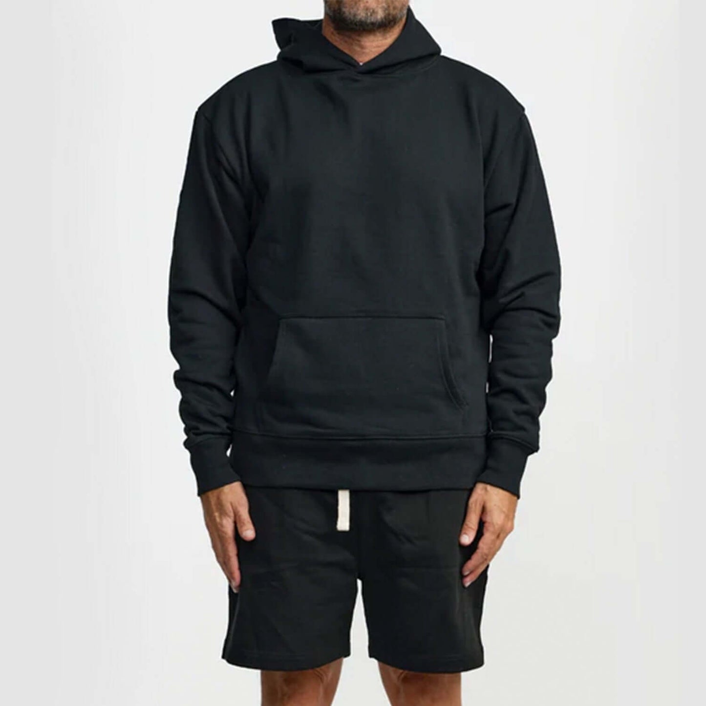 Man wearing a black WNSDY Essential Hoodie with a front pocket, showcasing comfort and style.