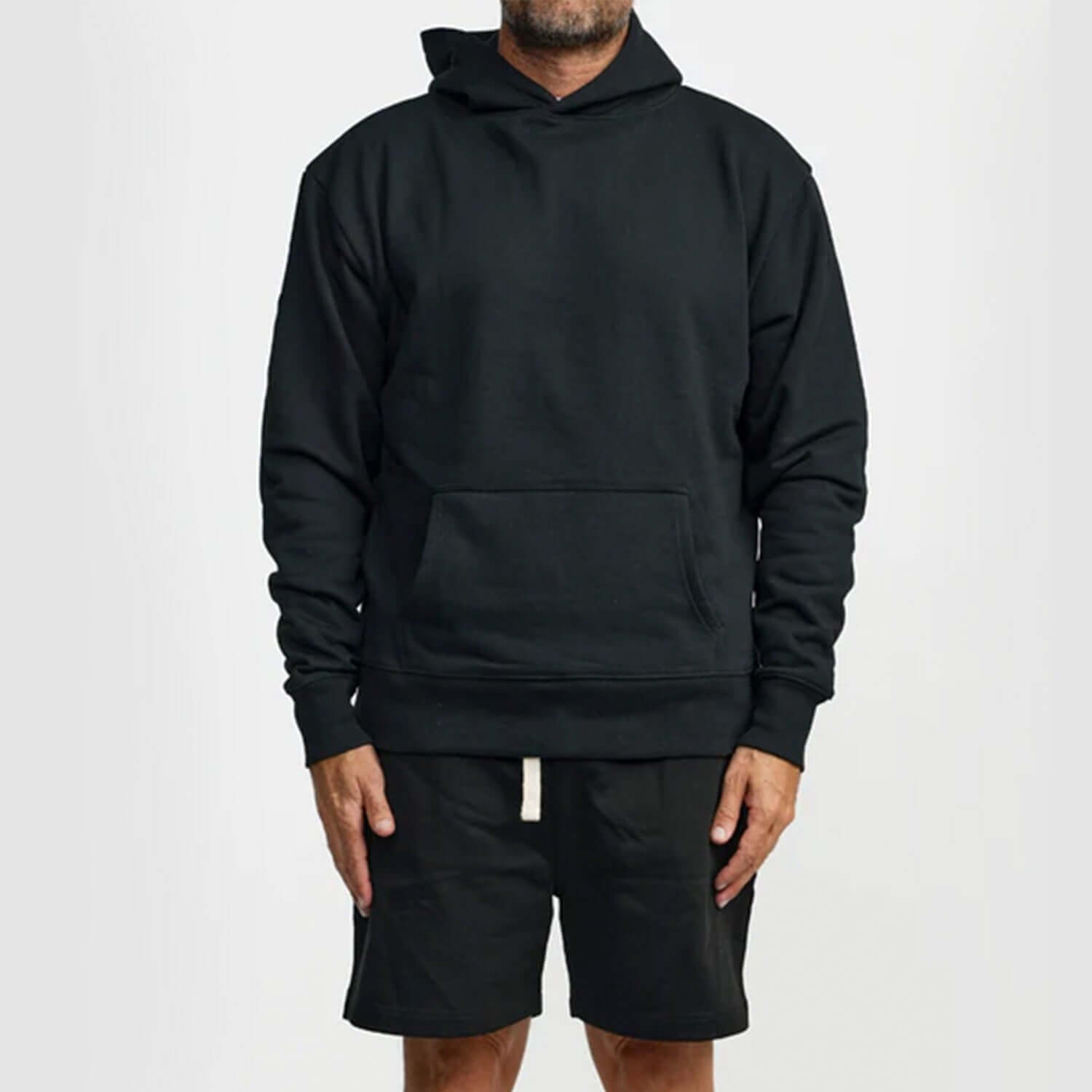 Man wearing a black WNSDY Essential Hoodie with a front pocket, showcasing comfort and style.