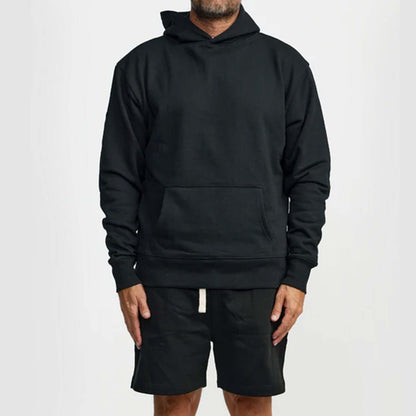 Man wearing a black WNSDY Essential Hoodie with a front pocket, showcasing comfort and style.