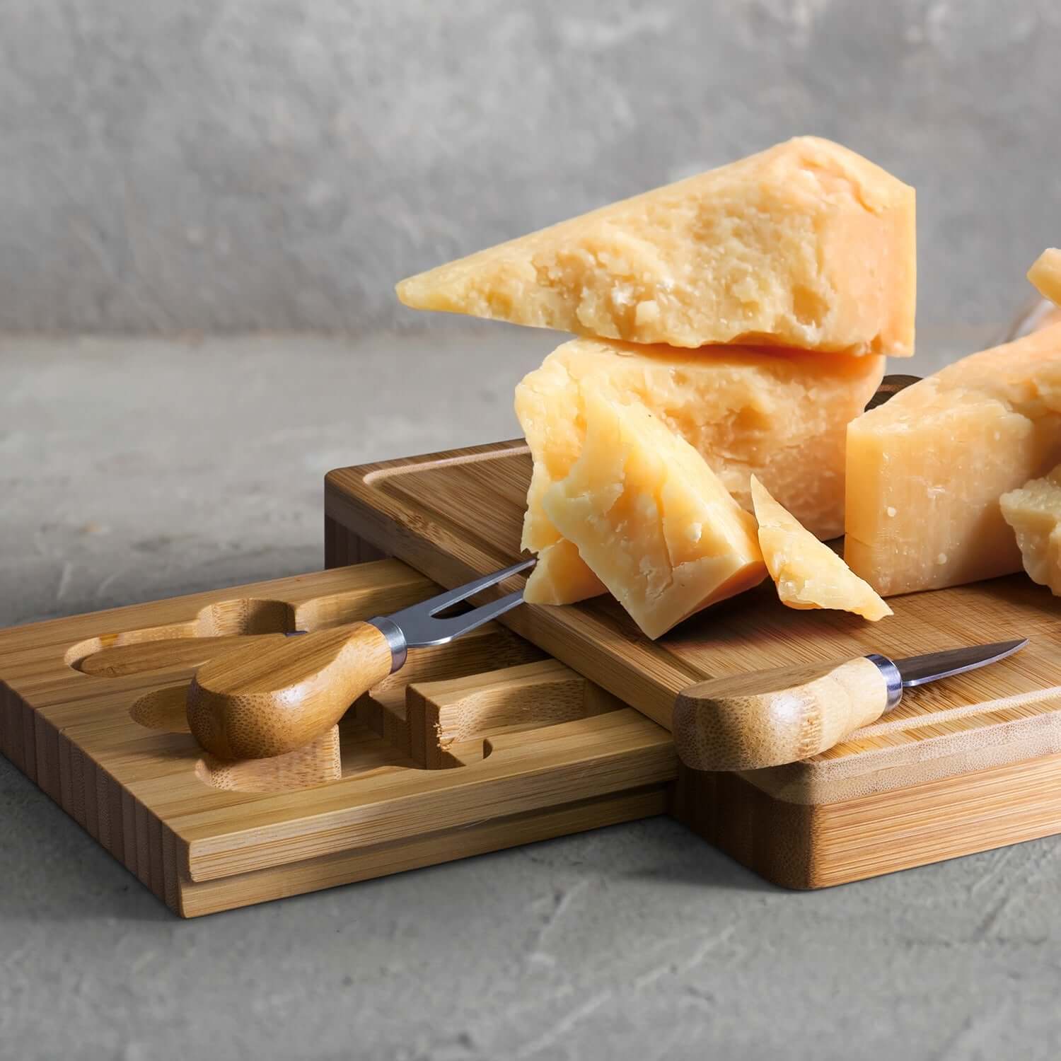 NATURA Kensington Cheese Board - Rectangle with cheese wedges and cutlery on a bamboo surface.