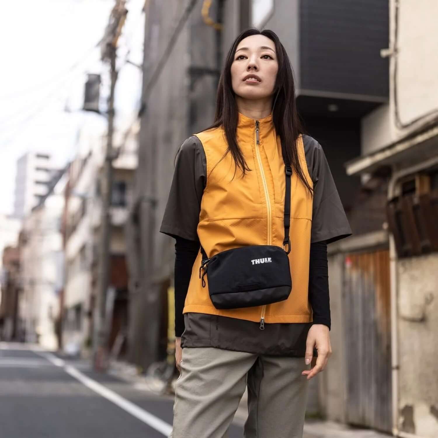Thule Paramount Crossbody 2L Bag worn by a model in urban setting, stylish and functional for urban adventures.