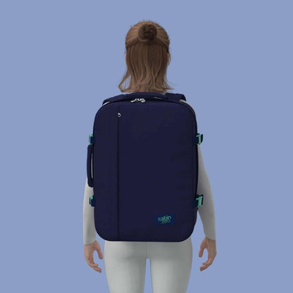 Cabinzero Classic Ultra Light Cabin Bag With Luggage Trackers 44L worn on back against a blue background.