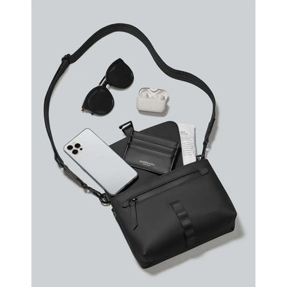 Gaston Luga Splash Crossbody Bag with sunglasses, phone, and AirPods on gray background.