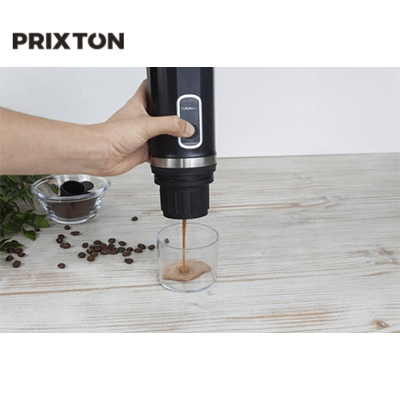 Prixton Roma Portable Coffee Maker brewing coffee into a glass with ground coffee beside it.