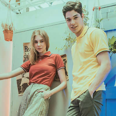 North Harbour 2700 Saffron Polo T-Shirt modeled by two individuals in a stylish setting.