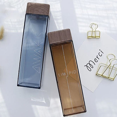 BPA Free Square Water Bottle with Bamboo Lid 500ml in blue and brown colors on a table with stationery items.