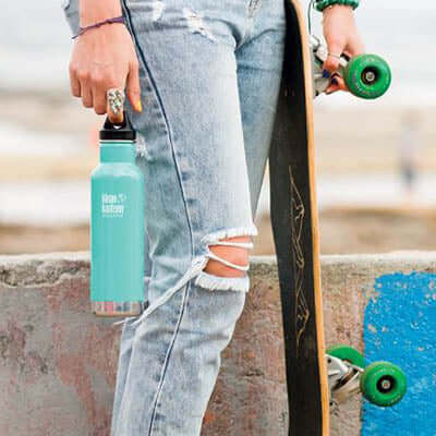 Klean Kanteen Insulated Stainless Steel Classic Bottle with Loop Cap held by a skateboarder in casual attire.