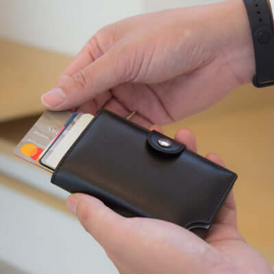 Person holding a BrandCharger Wally Porto RFID Leather Credit Card Holder with cards being inserted.