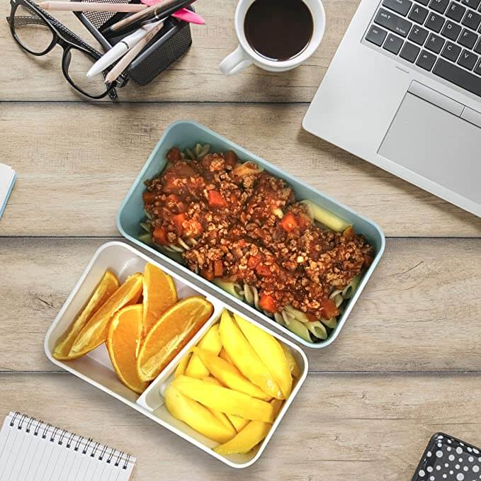 2-Tier Lunch Box with Rubber Tie filled with pasta and fruits on a desk with a laptop.