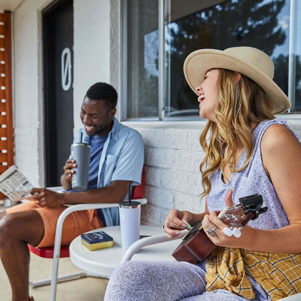 A man and woman enjoying their HydroFlask 32oz Tumblers while playing music and relaxing outdoors.