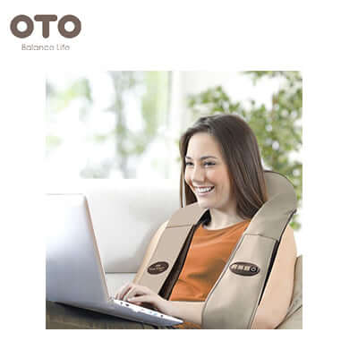 Woman using OTO Power Wrap for relaxation while working on a laptop at home.